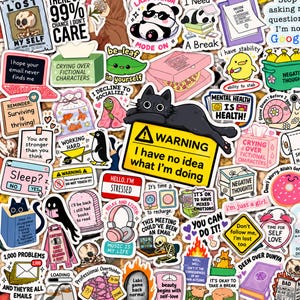 Puede incluir: Una colección de pegatinas de vinilo variadas con diversas ilustraciones humorísticas y motivacionales, incluyendo un gato negro en una señal de advertencia, un esqueleto, un panda, un pingüino y diseños de texto con frases como I have no idea what I'm doing.