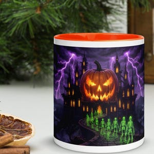 Puede incluir: Una taza de cerámica blanca con interior y borde de color naranja brillante. El exterior presenta una escena oscura y atmosférica de una calabaza brillante sobre un castillo gótico, con rayos púrpuras y una fila de esqueletos verdes.
