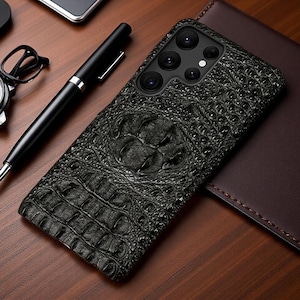 Puede incluir: Una funda para smartphone de color negro con un patrón texturizado de piel de cocodrilo. La funda tiene una forma rectangular con esquinas redondeadas y un recorte en la esquina superior izquierda para las lentes de la cámara y el flash.