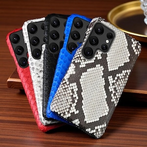 Puede incluir: Una colección de cinco fundas para smartphone con un patrón texturizado de piel de serpiente. Las fundas están disponibles en rojo, blanco, negro, azul y un estampado de piel de serpiente gris y blanco. Cada funda tiene una abertura negra.