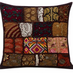 May include: A square throw pillow featuring a patchwork design of various fabric panels in shades of burgundy, brown, gold, and orange. The surface is decorated with intricate embroidery, metallic thread work, and small bead accents throughout.