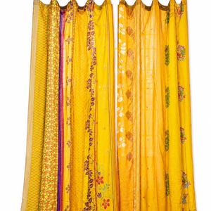 May include: A pair of yellow curtains hanging from a silver rod with tab tops. The curtains feature vertical panels with various patterns, including floral motifs, geometric shapes, and solid yellow sections with purple, green, and orange accents.