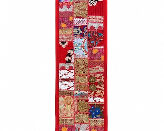 Könnte beinhalten: Ein langer, rechteckiger Tischläufer mit einem lebendigen Patchwork-Design aus verschiedenen bestickten Stoffen in Rot-, Gold-, Blau- und Weißtönen. Der Läufer ist mit einem einfarbigen roten Stoff eingefasst und an den Ecken mit kleinen roten Quasten versehen.