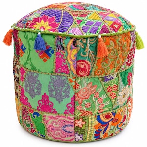 Op de afbeelding: Een cilindervormige poef met een patchworkontwerp van levendige, veelkleurige stoffen panelen. Het oppervlak is versierd met ingewikkeld borduurwerk, bloemmotieven en geometrische vormen in tinten groen, roze, oranje en blauw, afgewerkt met kleine hangende kwastjes.