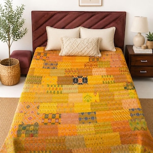 May include: A rectangular patchwork quilt featuring a vibrant array of yellow, orange, and gold fabric squares. The quilt displays various intricate patterns, including geometric shapes, floral motifs, and stripes, all joined by visible running stitch detailing.