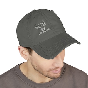 May include: A charcoal gray distressed baseball cap featuring a white embroidered graphic of a bull head and the text SH1T PROJECTS. The cap has a worn-in look with frayed edges on the brim and crown, a structured front panel, and a curved visor.