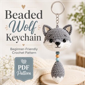 May include: A crochet wolf keyring featuring a grey and white head with black eyes and a nose, attached to a metal ring. Below the head are three small beads in blue, tan, and blue, followed by a grey and white tail. Text reads Beaded Wolf Keychain.