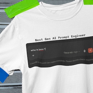 May include: A white t-shirt with a graphic print featuring the text Next Gen AI Prompt Engineer above a dark chat interface box containing the text who is json? and Opus 4.8 High. The shirt has blue sleeve cuffs and a crew neckline.