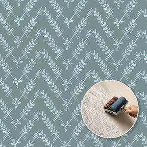 May include: A sage green wallpaper featuring a white chevron pattern composed of stylised leaf sprigs. An inset circular image shows a blue paint roller applying a similar leaf pattern onto a light surface, demonstrating the application process.