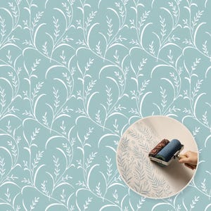 May include: A light blue wallpaper featuring a repeating white botanical pattern of curved stems and leaves. An inset circular image shows a patterned paint roller applying a similar fern-like design in blue ink onto a light-coloured surface.