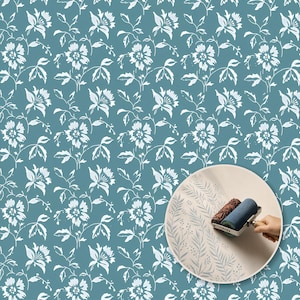 May include: A teal wallpaper pattern featuring a repeating white floral motif with stylized blossoms and leaves. A circular inset shows a textured paint roller applying a delicate fern-like pattern in a light blue ink onto a plain white surface.