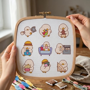 Peut inclure: Un tambour à broder carré en bois contenant un tissu blanc avec un motif au point de croix représentant neuf petits oiseaux clairs effectuant diverses activités, comme tenir un appareil photo, manger du pop-corn et utiliser une règle.