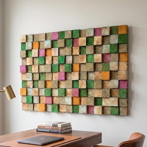 May include: A rectangular wall art piece composed of numerous small, square wooden blocks arranged in a grid. The blocks feature a mix of natural wood grain, green, pink, and orange painted finishes, creating a textured, multi-colored mosaic.