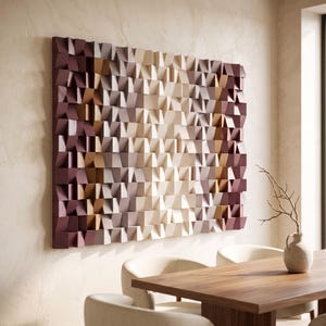 Puede incluir: Una gran pieza de arte mural rectangular compuesta por numerosos bloques de madera pequeños y salientes dispuestos en una cuadrícula. Los bloques presentan un esquema de color degradado, desde burdeos oscuro y marrón en los bordes hasta crema claro en el centro.