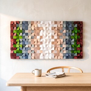 May include: A rectangular wall art piece composed of numerous small, square wooden blocks arranged in a grid. The blocks feature a gradient color scheme, transitioning from deep red and bright green on the outer edges to blue, beige, and white in the center.