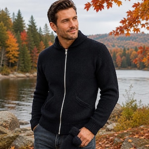 May include: A dark navy blue knit zip-up sweater featuring a shawl collar, long sleeves with ribbed cuffs, and two front pockets. The sweater is paired with dark grey denim jeans and a matching dark navy blue knit mitten held in one hand.
