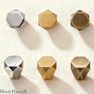 May include: Six hexagonal cabinet knobs arranged in two rows. The top row features a polished chrome, a brushed brass, and an antique bronze finish. The bottom row displays matching faceted designs in polished chrome, brushed brass, and antique bronze.