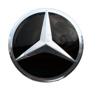 May include: A circular emblem featuring a three-pointed star design in a polished silver finish set against a glossy black background. The emblem is enclosed within a smooth, reflective silver circular border, creating a clean and metallic look.