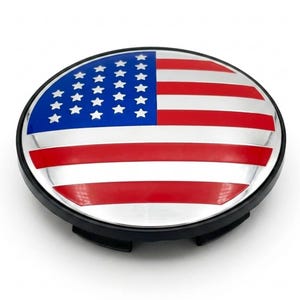 May include: A circular wheel center cap featuring a glossy finish with the American flag design. The emblem displays a blue field with white stars on the left side and horizontal red and white stripes across the surface, set within a black rim.