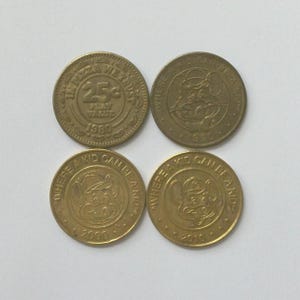 以下が含まれることがあります： 真鍮色の丸い金属製トークン4枚。1枚には「IN PIZZA WE TRUST」「25c PLAY VALUE」「1980」の文字が刻まれています。他の3枚にはネズミのキャラクター、「WHERE A KID CAN BE A KID」の文字、そして「1990年」「2000年」「2010年」の年号がそれぞれ刻まれています。