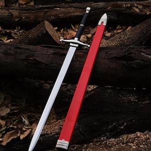 Pode incluir: Uma espada de metal prateado com cabo preto e guarda, acompanhada por uma bainha longa de cor vermelha brilhante com ponta e bocal de metal prateado. A lâmina da espada é reta e pontiaguda, refletindo a luz ao longo da sua nervura central.