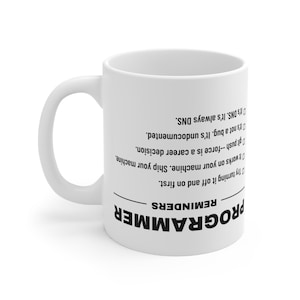 Puede incluir: Una taza de cerámica blanca con texto negro impreso al revés. El texto dice: PROGRAMMER REMINDERS, seguido de una lista: Try turning it off and on first, It works on your machine. Ship your machine, git push--force is a career decision, It's not a bug. It's undocumented, It's DNS. It's always DNS.