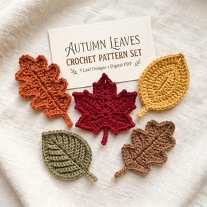 May include: Five crocheted leaves in orange, dark red, yellow, olive green, and brown arranged around a white card with the text Autumn Leaves Crochet Pattern Set, 5 Leaf Designs, Digital PDF printed in dark brown ink.