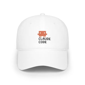 Puede incluir: Una gorra de béisbol blanca con un gráfico naranja pixelado de un pequeño personaje cuadrado sobre el texto negro pixelado CLAUDE CODE. La gorra tiene una corona estructurada, una visera curva y un botón en la parte superior central.