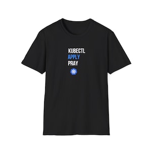 Puede incluir: Una camiseta negra de manga corta con el texto blanco KUBECTL, el texto azul APPLY y el texto blanco PRAY, seguido de un logotipo azul y blanco de un timón de barco de Kubernetes centrado en la zona del pecho de la prenda.