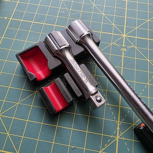 May include: Two silver metal socket extensions with knurled grips, one labelled Ko-ken 3760-75 and the other marked Made in Japan, resting in a black and red plastic storage organiser with individual slots for each tool component.