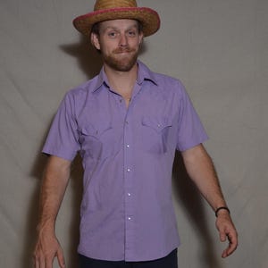 Op de afbeelding: Een witte keramische mok met een zwart handvat en de tekst "But First, Coffee" in een zwarte, vette letter. De mok staat op een houten oppervlak.