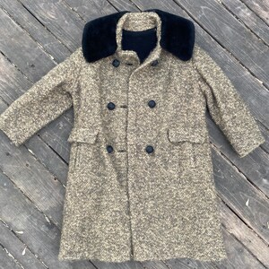 May include: A brown tweed coat with a black faux fur collar and double breasted closure.