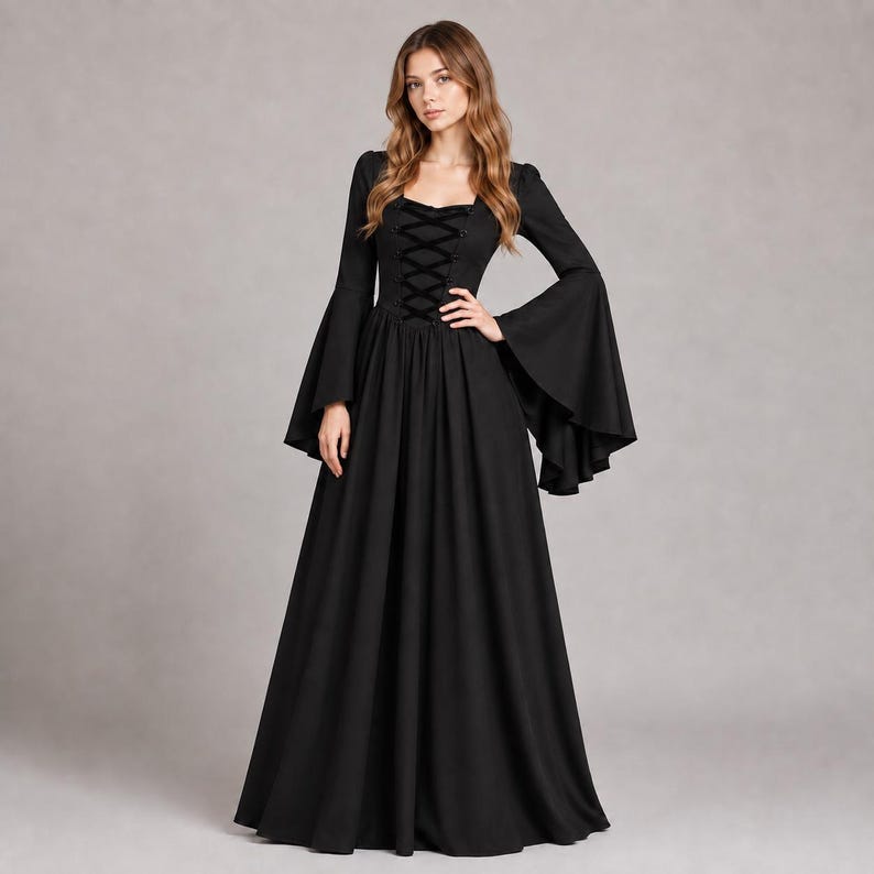 May include: A floor-length black dress featuring long, wide bell sleeves and a square neckline. The bodice includes a central vertical lace-up detail with black ribbon ties, transitioning into a full, flowing skirt that reaches the floor.
