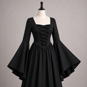 May include: A solid black dress featuring a square neckline, long flared bell sleeves, and a central bodice panel with black ribbon lace-up detailing. The garment has a fitted waistline that transitions into a full, flowing skirt silhouette.