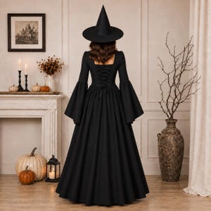 May include: A floor-length black dress with long flared sleeves and a lace-up corset back, paired with a tall pointed black witch hat. The garment features a fitted bodice that transitions into a full, flowing skirt, creating a silhouette.