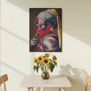 Può includere: Una stampa artistica incorniciata che raffigura una parodia della Ragazza col turbante, con il personaggio Deadpool che indossa un foulard blu e un orecchino di perla, con un dito guantato sulla maschera in un gesto di silenzio.