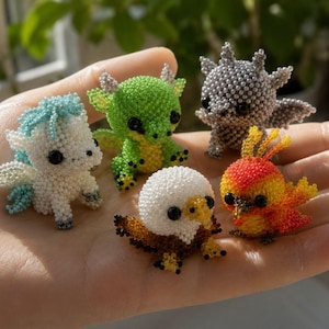 May include: Five miniature figurines crafted from tiny beads, including a white and light blue unicorn, a green dragon, a grey creature with wings, a bald eagle with brown and white feathers, and a small bird with orange and yellow plumage.