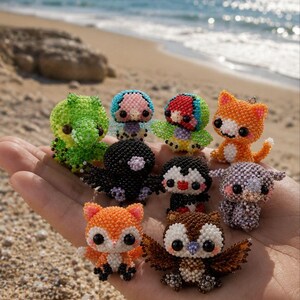 May include: A collection of eight small, handcrafted beaded animal figurines including a green dinosaur, a black bird, a penguin, an orange cat, a fox, an owl, and other colourful creatures, all constructed from tiny, multi-coloured glass beads.