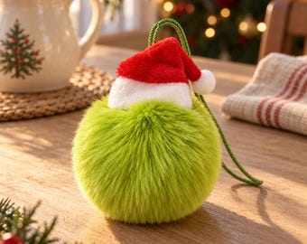 May include: A round, lime green faux fur ornament topped with a miniature red and white Santa hat. The ornament features a green braided hanging cord and has a soft, textured, spherical appearance, designed for holiday decoration.