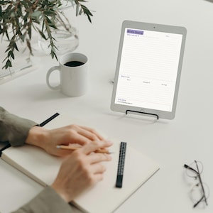 May include: A digital tablet on a black stand displaying a Brain Dump planner template with sections for tasks, scheduling, and goals. The screen shows text including Brain Dump, Sort it out, Do it, Schedule it, Let it go, and One thing.