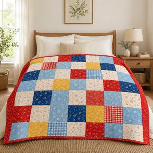 May include: A patchwork quilt featuring a grid of square fabric blocks in red, blue, yellow, and cream. The pattern includes floral prints, small gingham checks, and solid colors. The quilt is draped over a bed with white pillows and a wooden headboard.