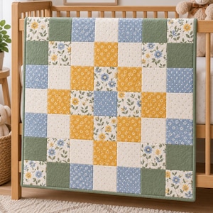 Könnte beinhalten: Eine Patchwork-Steppdecke mit einem Raster aus quadratischen Stoffbahnen in abwechselnden Mustern und Farben. Das Design umfasst florale Drucke in Gelb, Blau und Grün sowie einfarbige salbeigrüne Quadrate und cremefarbenen Stoff mit kleinen Punkten.