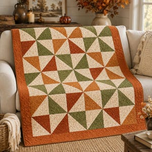 Peut inclure: Un quilt présentant un motif géométrique de triangles dans des tons orange brûlé, vert olive et crème. Le design se compose de blocs carrés répétitifs avec une disposition en moulinet, finis par une bordure orange brûlé et des coutures.