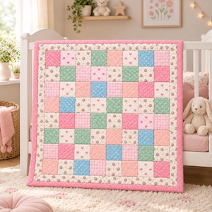 May include: A square patchwork quilt featuring a grid of alternating fabric squares in pastel pink, light blue, and sage green. The quilt displays various patterns including small floral prints, white hearts, polka dots, and gingham checks, all framed by a solid pink border.