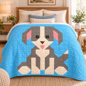 Pode incluir: Uma colcha azul brilhante com um grande design geométrico de cão em estilo pixel-art em tons de cinzento escuro, creme e rosa. O cão é representado numa posição sentada com orelhas caídas, uma cauda pontiaguda e uma pequena língua rosa.