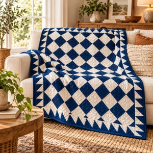 May include: A quilt featuring a repeating diamond pattern in deep blue and white, finished with a triangular sawtooth border. The fabric displays intricate stitching throughout, creating a textured surface across the entire textile piece.