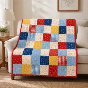 May include: A patchwork quilt featuring a grid of square fabric blocks in red, blue, yellow, and cream. The design incorporates various patterns including small floral prints, gingham checks, and solid colors, all bordered by a red fabric trim.