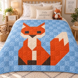 Könnte beinhalten: Eine blaue Patchwork-Decke mit einer großen, stilisierten Grafik eines orange-weißen Fuchses. Die Decke besteht aus kleinen quadratischen Stoffblöcken in verschiedenen Blautönen, wobei das Fuchsmotiv in Orange, Weiß, Dunkelbraun und Schwarz zentriert ist.