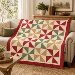 Puede incluir: Una colcha rectangular con un patrón repetitivo de molinillos en tonos crema, verde bosque y rojo intenso. La colcha está rematada con un borde rojo sólido y muestra costuras intrincadas en toda la superficie de la tela.
