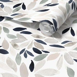 May include: A roll of wallpaper featuring a white background with a repeating pattern of watercolor-style leaves in shades of dark navy blue, muted sage green, and soft beige. The leaves are arranged in a scattered, organic layout across the surface.